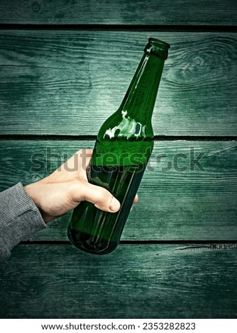 Vignetting Photo of Person hold a Bottle of the Beer on the Wooden Wall closeup