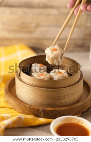 Dimsum is a unique food from Hong Kong which contains shrimp, fish or meat. which is served on a special bowl of dim sum with a small bowl of spicy sauce Royalty-Free Stock Photo #2353295705