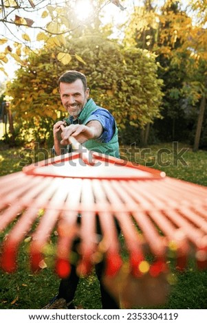 Picture of a man having fun with leaves rake during autumn cleanup in garden
