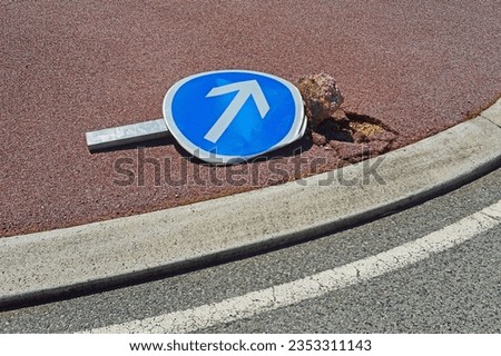 A broken road sign on a roundabout