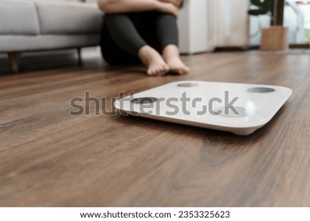 Sad obese woman with fat upset bored of dieting Weight loss fail  Fat diet and scale sad fat asian woman  weight scale at home weight control. Royalty-Free Stock Photo #2353325623