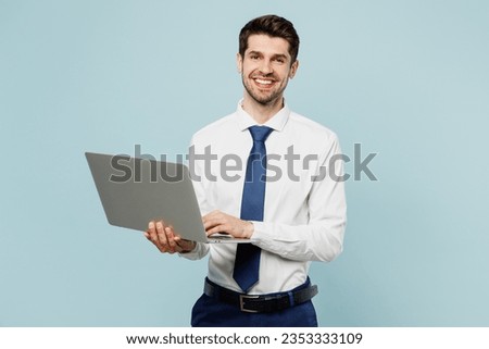 Young happy smiling employee IT business man corporate lawyer wear classic formal shirt tie work in office hold use laptop pc computer isolated on plain pastel light blue background studio portrait