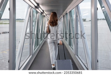 Businesswoman boarding the plane with carry-on Royalty-Free Stock Photo #2353350681