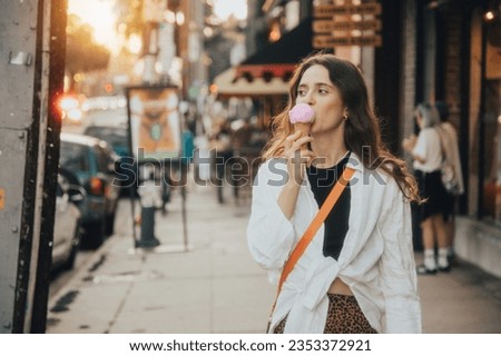 Portrait of a beautiful young woman, licking ice cream, walking on the city street. Los Angeles. California. The USA. Royalty-Free Stock Photo #2353372921