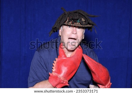 Photo Booth. Lobster Claws. A man wears Lobster Claws over his hands as he poses for pictures while in a PHOTO BOOTH. Photo Booths are Fun. Photo Booth Fun. Lobster or Crab Claws. Sea Creature. Humor.