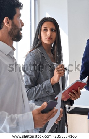 Busy diverse workers team young people standing having discussion. Young professional Indian executive sharing ideas with colleagues group discussing marketing project strategy at meeting in office. Royalty-Free Stock Photo #2353374165
