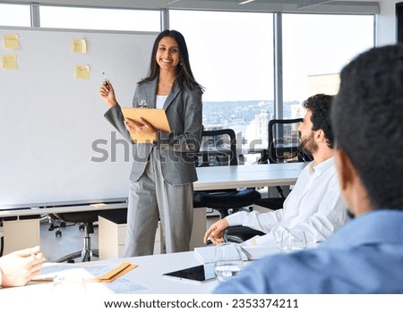 Happy Indian business woman professional presenter giving presentation at corporate group meeting in office. Busy diverse team business people working on corporate strategy on conference training.