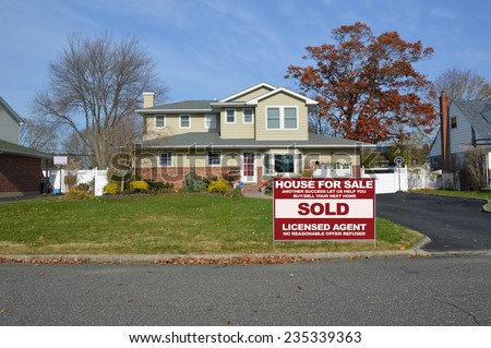 Real Estate sold (another success let us help you buy sell your next home) sign Suburban Mcmansion style home autumn day residential neighborhood blue sky clouds USA