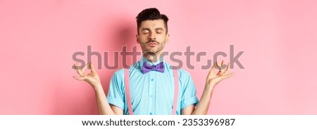 Young guy in bow-tie standing calm and peaceful, meditating with hands in mudra zen gesture and closed eyes, practice yoga to relax, standing over pink background.
