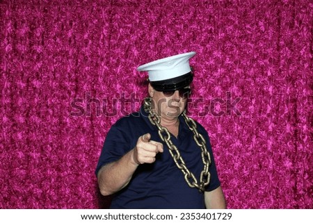 Photo Booth. A man Smiles and Poses while his Pictures are taken in a Photo Booth at a Wedding or Birthday Party. People love to dress up in Costumes and have their Photos Taken in Photo Booths. 