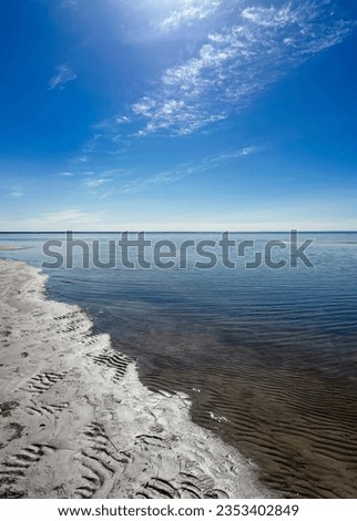 Seascape with wet sand on the beach and beautiful sea water against a blue sky on a clear sunny day