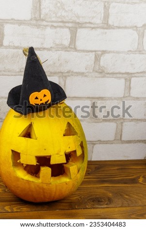 Spooky Halloween pumpkin jack-o-lantern in witch hat on a wooden background
