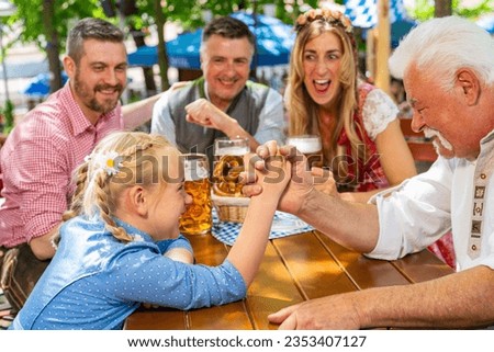 Happy family practicing the high art of arm wrestling in a beer garden ir oktoberste