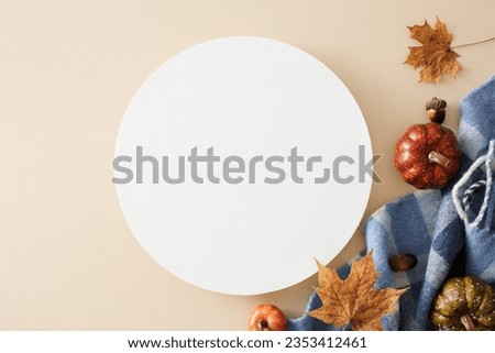 Immerse yourself in the captivating autumn vibe. Top view photo of warm plaid, pumpkins, acorns, dry autumn leaves on pastel beige background with blank circle for promo or text