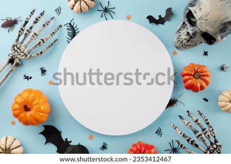 Mixing laughter, scares, and treats for the ultimate Halloween bash. Top view flat lay of skeleton hands, skull, pumpkins, halloween decor on light blue background with blank circle for promo or text
