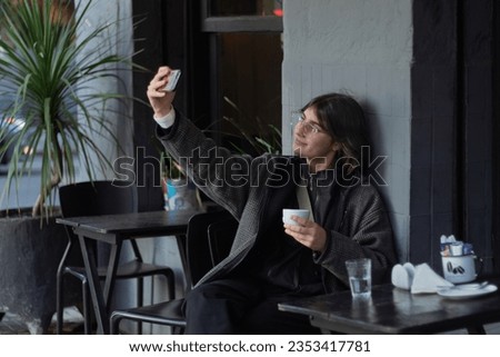 Woman taking a selfie with a cup of coffee on her hand 