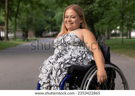 Smiling Happy Young Woman With Short Stature On Wheelchair Enjoys Time in Green Park At Summer Day. Female Adult With Disability. Copy Space For Text. Horizontal Plane. High quality photo Royalty-Free Stock Photo #2353422865