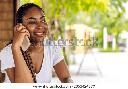 Portrait of of smiling happy african woman relaxing use technology of smartphone at city.Young african creative girl looking at screen typing message and playing game online or social media