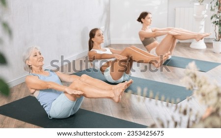 Elderly woman doing pilates exercises in group in fitness studio Royalty-Free Stock Photo #2353425675