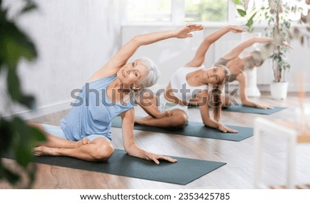 Active women three generations exercising during yoga class in fitness center - vakrasana pose. High quality photo Royalty-Free Stock Photo #2353425785