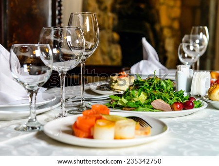 Served for holiday banquet restaurant table with dishes, snack, cutlery, wine and water glasses. European food. Royalty-Free Stock Photo #235342750