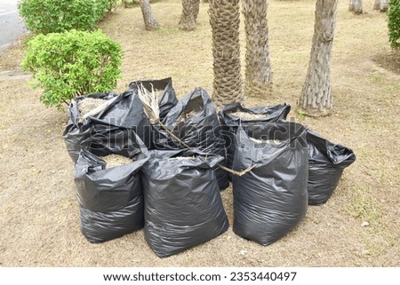 Black garbage bags containing grass clippings in a natural park. Waste separation, environmental protection. Natural and biodegradable waste