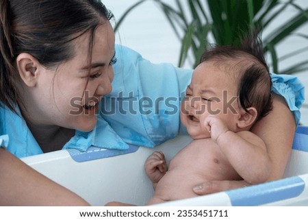 Asian over weight mother bathing her son in bathtub, baby don't want to take a bath newborn baby care concept