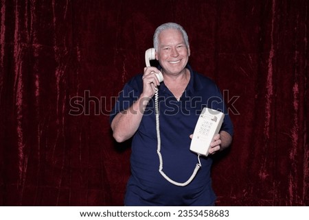 Photo Booth. Telephone. Old School Telephone. A man listens to a Sales Pitch on his Old School Wired Telephone while having his picture taken in a Photo Booth. Photo Booths are loved by everyone. 