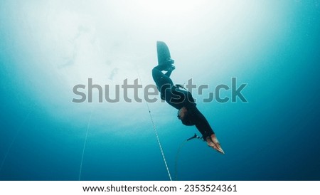 Freediving on the rope in a sea. Male freediver descends along the rope in monofin Royalty-Free Stock Photo #2353524361