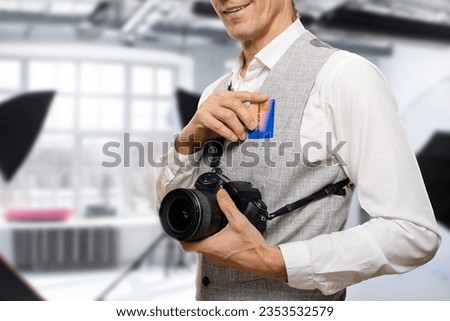 Young male photographer using banking accountd to make cashless transactions. The payment card symbolizes the interconnectedness of commerce and artistry