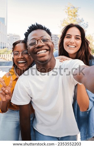 Vertical portrait of a group of multiracial young student people smiling taking a selfie together. Happy african american teenager laughing with his cheerful friends. Classmates on friendly meeting Royalty-Free Stock Photo #2353552203