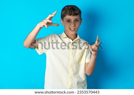 Beautiful kid boy wearing casual shirt Shouting frustrated with rage, hands trying to strangle, yelling mad.