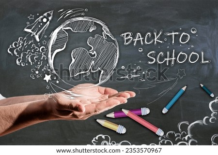 Close up of man hand holding abstract back to school sketch with pencils and rocket on chalkboard wall background. Education and knowledge concept