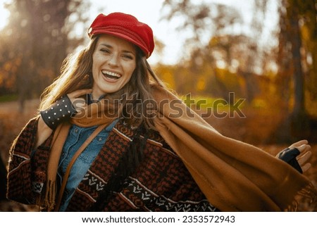 Hello autumn. Portrait of happy elegant 40 years old woman in red hat with scarf and gloves in the city park.