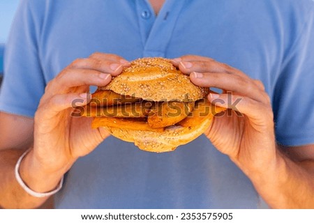 Man hands holding Pane e panelle - chickpea flour fritters in mafalda bread roll, sandwiche, a typical street food of Palermo, Sicily, Italy. Easy and delicious vegan food. Royalty-Free Stock Photo #2353575905