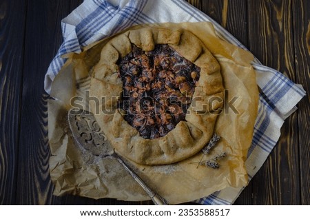 French plum fruit galette pie on the black wooden wood desk with linen fabric textile and antique vintage silver cutlery