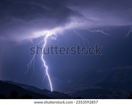 Close-up of massive lightning bolt by rural landscape against stormy night sky