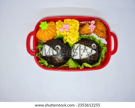 school lunch boxes of rice balls decorated like sharks served with eggs, fried chicken and a slice of orange