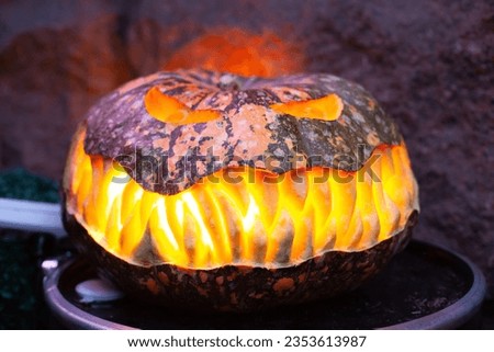 Orange creepy illuminated scary pumpkin. Halloween decoration at home. Festival Halloween spooky glowing Jack-o'-lantern pumpkin on a porch. Carved Halloween pumpkin. 