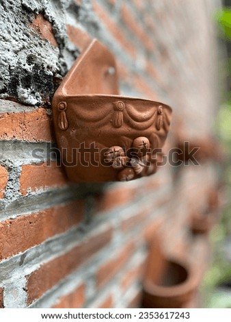 a flower pot stuck to a red brick wall against a background of other flower pots