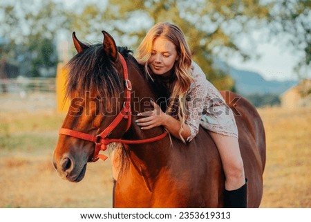 Portrait of a young beautiful cute blond girl is hugging her horse at sunset. Equitation concept.