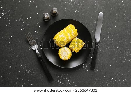 Plate of boiled corn cobs on black background