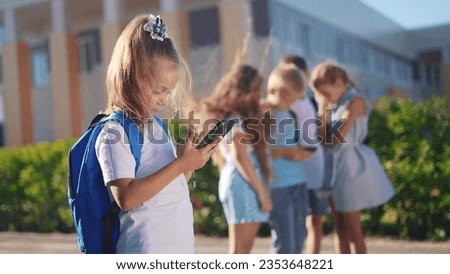 pupils stand in the schoolyard and look at phones. business concept of modern lifestyle training and development. a lifestyle group of students playing on the phone in the backyard of the school Royalty-Free Stock Photo #2353648221