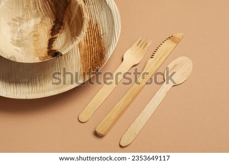 Wooden cutlery with plate and bowl on brown background, closeup