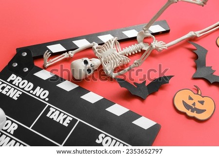 Composition with clapperboard, skeleton, paper bats and pumpkins on red background. Halloween celebration