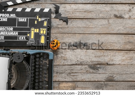 Typewriter with clapperboard and Halloween decor on brown wooden background