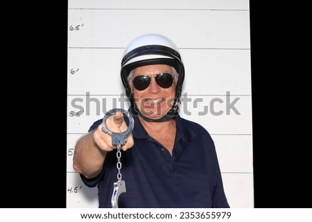 Photo Booth. Motorcycle Police Officer in front of a Police Booking Sign. When under arrest you get your Mug Shot Picture taken by the Police. Police Hand Cuffs. Cops are important people. Friendly. 