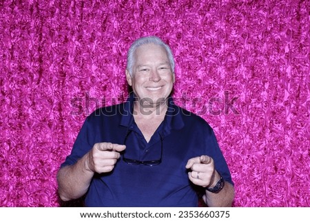 Photo Booth. A man Smiles and Laughs as he poses for his picture to be taken while in a Photo Booth at a Party. Photo Booths are loved at Weddings and all Parties. Guest pose for photos. Photo Booth. 