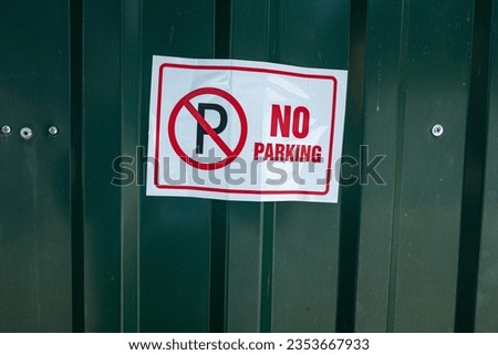 No Parking sign on a green metal fence.