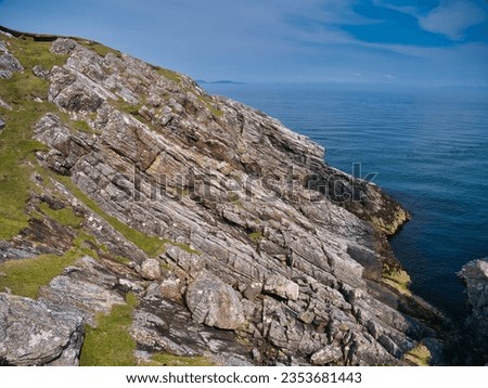 Inclined rock strata near the Eilean Glas Lighthouse on Scalpay - Outer Hebrides Thrust Zone Mylonites Complex - Mylonite. Metamorphic bedrock formed between the Archean Eon and Ediacaran periods. Royalty-Free Stock Photo #2353681443